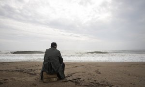 Hombre mirando el mar en una playa con cielo nublado. Imagen de archivo / Pixabay