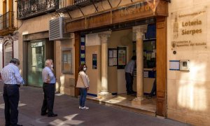 Varias personas hacen cola en la puerta de una administración de Loterías en la calle Sierpes de Sevilla. /EFE