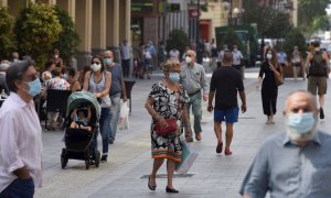 Varias personas con mascarilla caminan por las calles de Huesca . EFE/ Javier Blasco