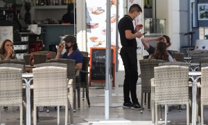 un camarero atiende a unos clientes en la terraza de un bar. EFE/Ana Escobar