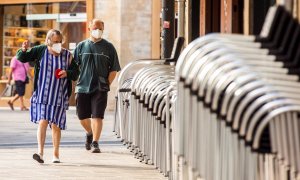 Un hombre y una mujer pasan ante la terraza recogida de un bar en el centro de Vitoria este miércoles, en el que se ha sabido que tres personas fallecieron la semana pasada en Euskadi con infección por coronavirus. EFE/ David Aguilar