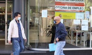 Dos personas con mascarilla pasan por una oficina de empleo de Madrid. E.P./Marta Fernández