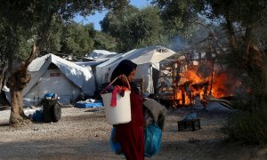 Una mujer trata de recuperar alguna de sus pertenencias, mientras el fuego sigue consumiendo las carpas del campamento de refugiados de Moria. - EFE