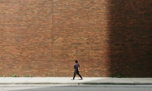 Una mujer camina junto a un muro de ladrillo.- Greg Shield / Unsplash