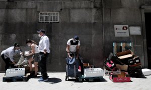 Dos personas recogen alimentos que les dan dos voluntarios a las puertas de la Parroquia Santa María Micaela donde han acudido para recibir una ayuda alimentaria. Eduardo Parra / Europa Press / Archivo