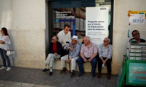 Un grupo de pensionistas sentados en la ventada de una sucursal del banco BBVA en Málaga.