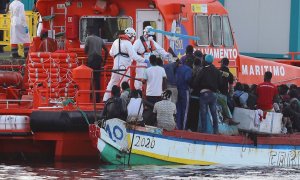 El personal de Salvamento Marítimo ayuda a los inmigrantes a desembarcar en el puerto de Arguineguín.