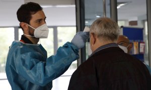 Personal sanitario del SERMAS toma la temperatura a una persona en la entrada de una residencia de mayores.