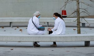 Dos sanitarias conversan en un banco en las inmediaciones del hospital Vall d'Hebron de Barcelona