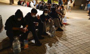 Un grupo de migrantes sentados frente a la Delegación del Gobierno en Las Palmas de Gran Canaria.