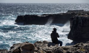 Un joven observa romper las olas en un fuerte oleaje en Menorca.