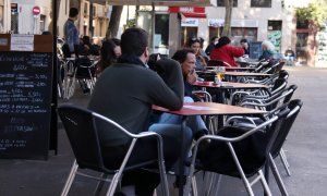 Una cambrera netejant una taula d'una terrassa del bar Las Euras a la plaça de la Vila de Gràcia de Barcelona.