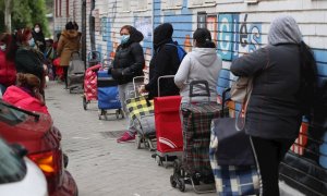 Varias personas esperan en la fila para recoger alimentos proporcionados por la Asociación de vecinos de Aluche. (RODRIGO JIMÉNEZ | EFE)