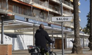 Un ciclista passa pel passeig marítim de Salou, amb els establiments tancats.