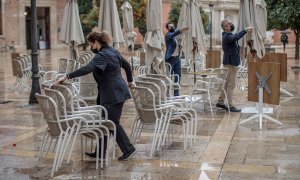 Unos trabajadores de un restaurante del centro de Valencia recogen la terraza. EFE/Biel Aliño