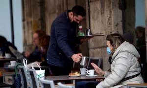 Un camarero sirve un café en la terraza de un bar en Vigo.