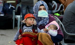 Una mujer sostiene a dos niños mientras abandona Gaza.