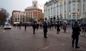 Efectivos policiales vigilan a asistentes a una sentada improvisada en la plaza de Neptuno de Madrid.