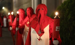 Nazarenos vestidos con túnica blanca y roja y capuz rojo durante una procesión en 2019.