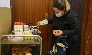 Una dona omple un carro de menjar a un punt de distr​ibució d'aliments de Cáritas a Les Corts.