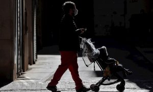 Un hombre pasea con un carrito de bebé por la ciudad de València.