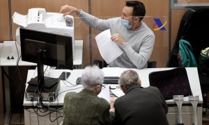 Un empleado de la Agencia Tributaria atiende a dos personas para la tramitación de su declaración del IRPF, en la Campaña de la Renta. E.P./Eduardo Parra