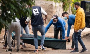 Unos inmigrantes y personal de la ONG Accem, que gestiona el campamento humanitario de Las Raíces, trasladan a uno de los heridos en los altercados.