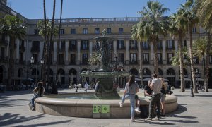 Uns joves descansen i parlen a la font de la plaça Reial