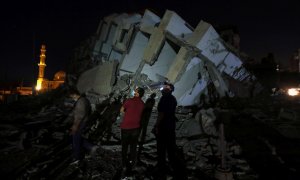 Varios palestinos en el lugar donde un edificio fue destruido por los ataques aéreos israelíes en medio de un estallido de violencia israelí-palestina