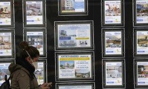 Una mujer pasa junto a una inmobiliaria en Bilbao. Fotografía de archivo.