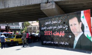 Varios peatones pasa junto a un cartel electoral que muestra al presidente sirio, Bachar Al Assad.