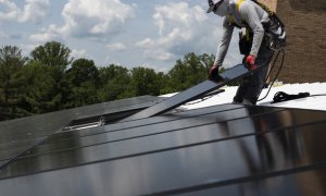 Un operario coloca una placa solar en el tejado de un edificio de EEUU.