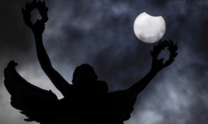 El eclipse solar parcial de este jueves se aprecia detrás de la estatua del parque del Jubileo en Bruselas, Bélgica.