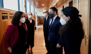 La presidenta de la Comunidad de Madrid, Isabel Díaz Ayuso (i) conversa con la portavoz de Vox en la Asamblea, Rocío Monasterio (d) en presencia del líder partido de ultradereha, Santiago Abascal (2d), en los pasillos de la Asamblea de Madrid, en una foto