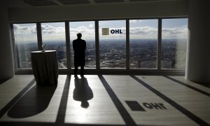 Un hombre mira a través de un ventanal de la sede en Madrid de la constructora OHL. REUTERS/Andrea Comas