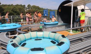 Visitants fent cua i altres ja en un matalàs inflable en una atracció del parc aquàtic Waterworld, a Lloret de Mar.