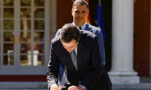 El presidente del Gobierno, Pedro Sánchez (detrás) y el presidente de la CEOE, Antonio Garamendi, durante la firma del acuerdo para la reforma de las pensiones este jueves en el palacio de la Moncloa en Madrid.