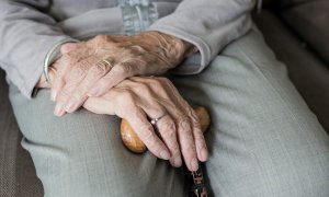 Una mujer mayor agarra entre sus manos un bastón.