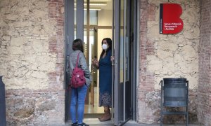 L'entrada de l'oficina del Servei d'Atenció, Recuperació i Acollida (SARA) de Barcelona, amb la seva directora, Ruth Capdevila, parlant a la porta amb una noia.