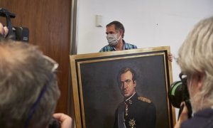 15 de junio de 2020. Varios fotógrafos captan el momento en que un operario retira del retrato del rey emérito Juan Carlos I de la Sala de Gobierno del Legislativo foral del Parlamento de Navarra, el 15 de junio de 2020