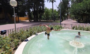 Dos jóvenes se refrescan en una fuente en el Jardín del Malecón de Murcia.