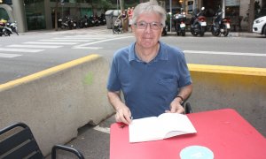 Ramon Aymerich fulleja el seu llibre durant l'entrevista.