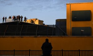 Un policía observa a un grupo de migrantes internados en el CIE de aluche pidiendo su libertad, tras ser declarado el primer confinamiento por la pandemia de covid-19, el 17 de marzo de 2020, Madrid, España.