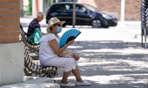 Una anciana con mascarilla se abanica sentada en un banco en Madrid. E.P./A. Pérez Meca