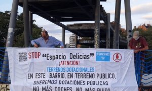 Dos vecinos de Madrid colocan una pancarta contra el macroproyecto 'Espacio Delicias'.