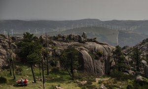 Una familia come en el área recreativa del Monte Pindo, con los molinos al fondo en las montañas.