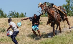 Un agente de la patrulla fronteriza de Estados Unidos a caballo intenta detener a dos migrantes haitianos en el río Grande (Texas).