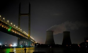 Un hombre camina a la orilla del río Huangpu cerca de una central eléctrica de carbón en Shanghai, China.