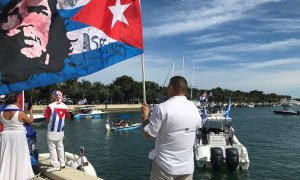 Un manifestante ondea hoy una bandera cubana con la imagen del Che Guevara y la palabra "Asesino", en la dársena situada en la bahía de Vizcaya en Miami.