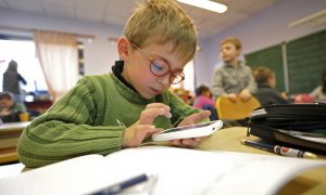 Un niño comprueba un dispositivo móvil durante una clase en un colegio.